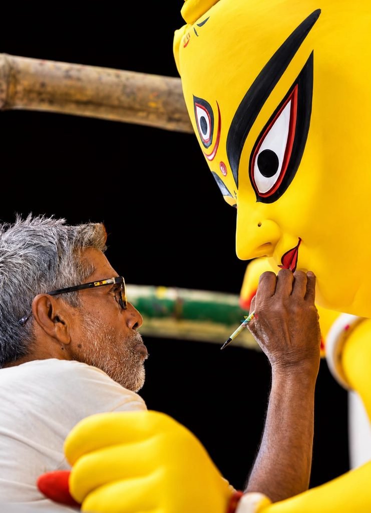 Artist painting a Durga Puja mascot during Durga Puja 2026